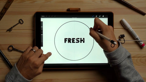 A hand draws a perfect circle around the word "Fresh" in Procreate