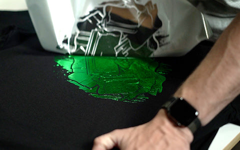 a hand peels green foil off a black shirt