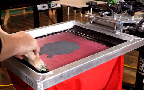 person printing a dye blocker base on a red shirt