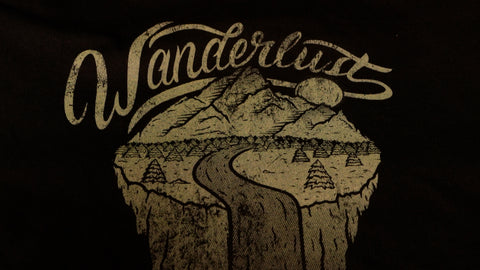 A print reading "wanderlust" with a mountain and river scene printed on a t-shirt