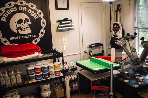 A screen printing shop with a flash dryer, ink, and skull poster