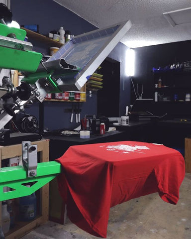 A screen printing press with a red shirt on the platen