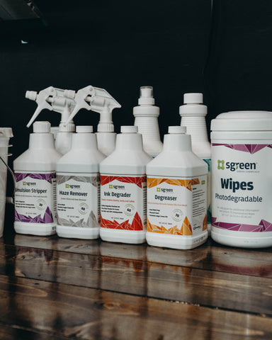 A line of Sgreen cleaning chemicals sitting on a counter with a black background