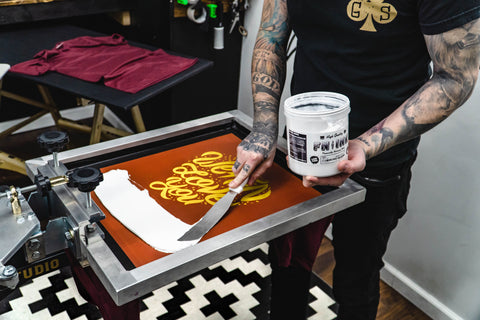 A hand swipes white ink onto an orange screen