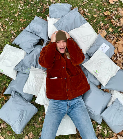 a man wearing a red jacket and a beanie lies among a pile of packages