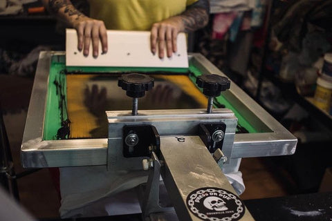 A printer pulls a squeegee along a screen