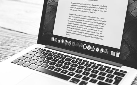 Una imagen en blanco y negro de un MacBook con un documento de Word en la pantalla