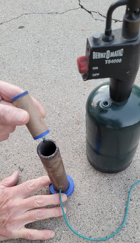 Inserting a homemade fireworks mini-shell into it's mortar tube for firing