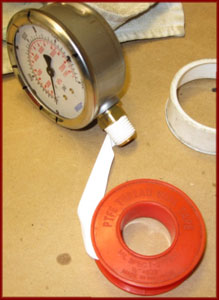 Wrapping the fitting on a pressure gauge with teflon tape