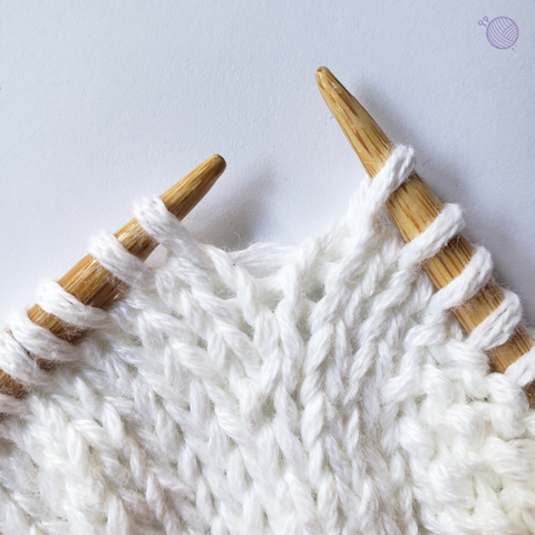 Bamboo knitting needles working with white yarn.