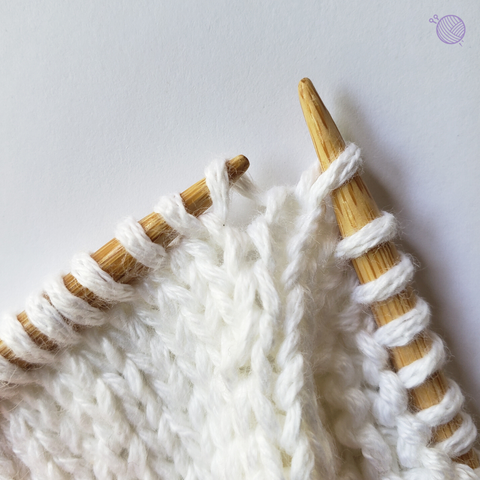 Bamboo knitting needles working with white yarn.