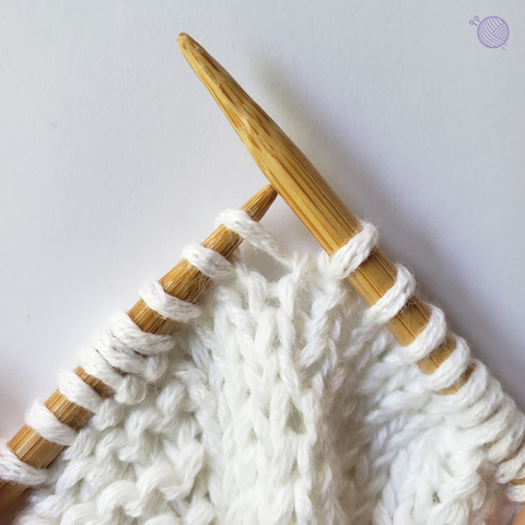 Bamboo knitting needles working with white yarn.