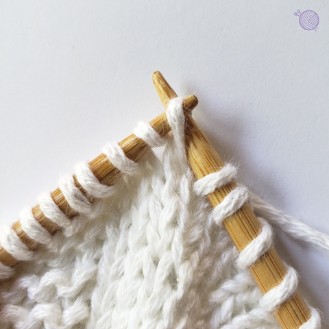 Bamboo knitting needles working with white yarn.