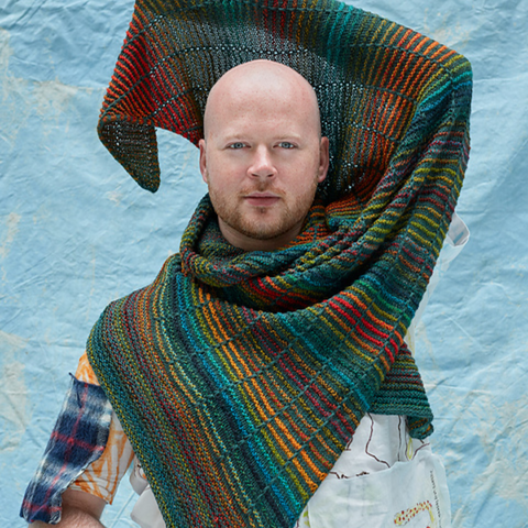 Man wearing a dark green and rainbow striped scarf.