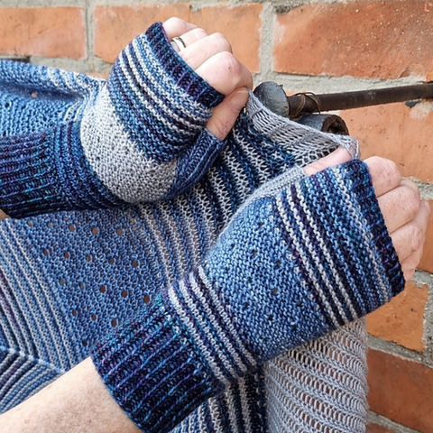 Pair of hands wearing fingerless mittens in shades of blue.