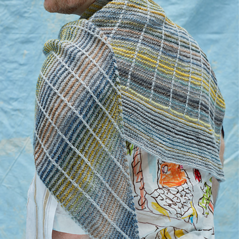 A shawl in light gray and multicolored stripes against a blue background.