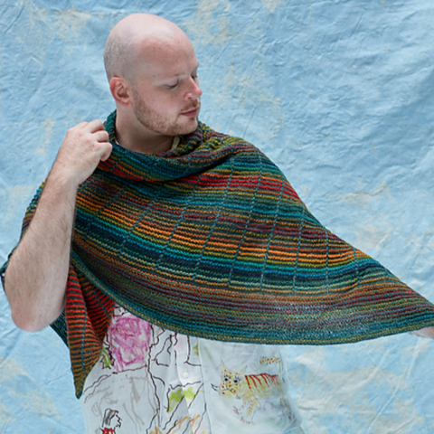 Man wearing a dark green and rainbow striped shawl.