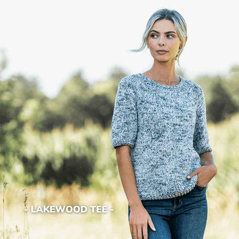 Blue and white sweater with elbow length sleeves being modeled outdoors.