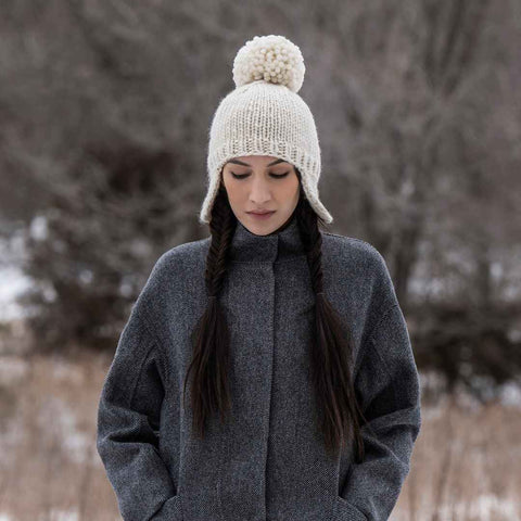 Model wearing a white Winnipeg Hat with a large, fluffy pom pom.