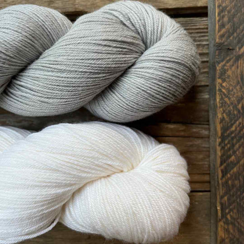 Cascade Heritage Silk in the colors Gray and White on a wooden background.