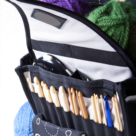 Organized crochet hooks in a case with some green, blue and purple yarns.