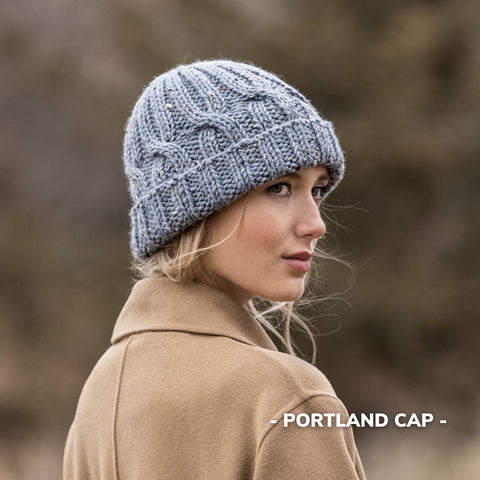 Model wearing a light blue gray knit hat with simple cables.