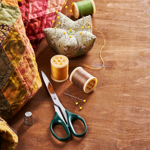 Quilting supplies including thread and scissors on a wooden table.