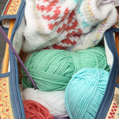 Open project bag with mint blue and green yarn and a white colorwork sweater.