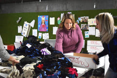 Two individuals sorting through donated mittens for Mittens for Detroit.