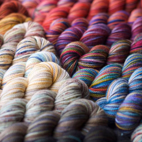 A close up image of Koigu KPPPM yarns in the yellow, blue, red, purple, and brown colorways.