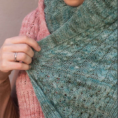 Close up of cables and twisted stitches on soft green blue knit shawl.