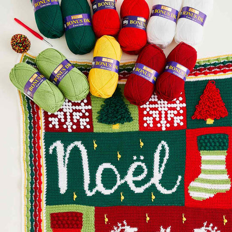 Nordic Noël blanket and the yarn skeins needed to make it.