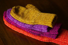 Pairs of mittens in various sizes stacked on top of one another.