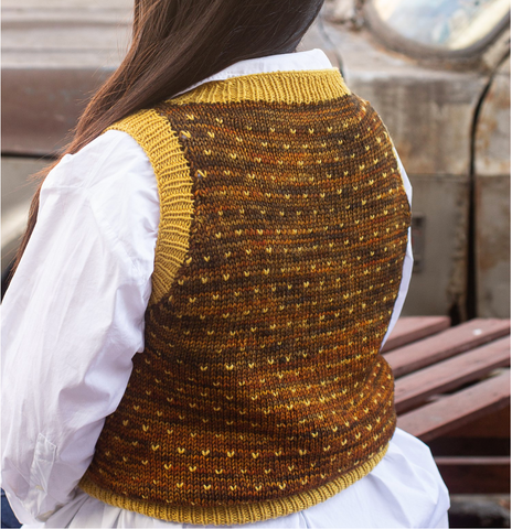 Gold and brown knit vest with little pops of gold worn over a white button down shirt.