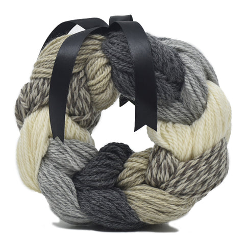 Circular bundle of neutral yarns tied with a black satin ribbon.