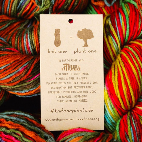 Skeins of bright multicolored yarn with an Urth Yarns tag explaining their #knitoneplantone pledge.