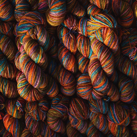 Skeins of mulitcolored yarn being lit by a ray of sunshine.