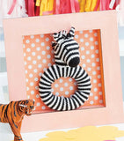 Zebra ring toy in a pastel orange shadow box.