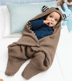 Child wrapped in a brown blanket shaped like a bear.