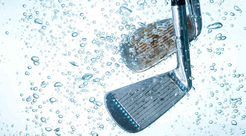 golf clubs immersed in water being cleaned