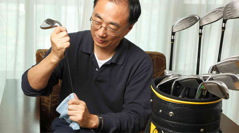 person cleaning the shaft of a golf club