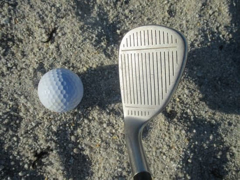 sand wedge and golf ball in a bunker