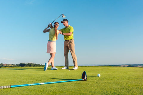 Woman getting a lesson on the correct golf posture