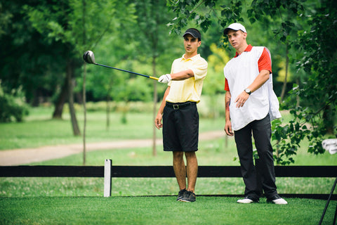 golfer strategizing with caddy before tee shot