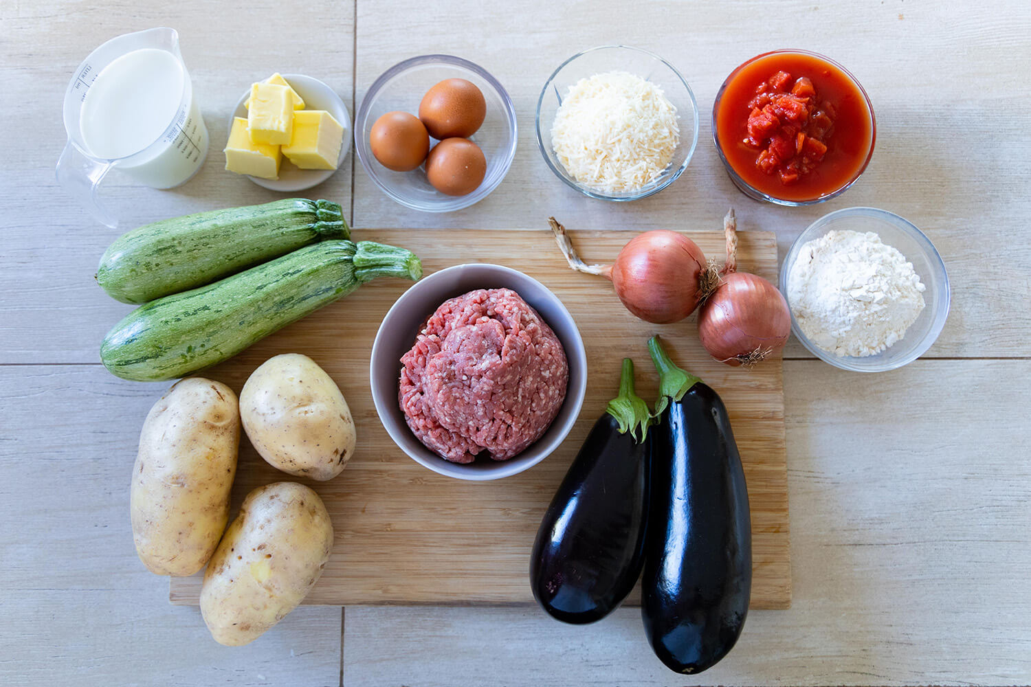 ingredients for moussaka, greek casserole, minced beef, eggplants, potatoes, zucchini, eggs, canned tomatoes