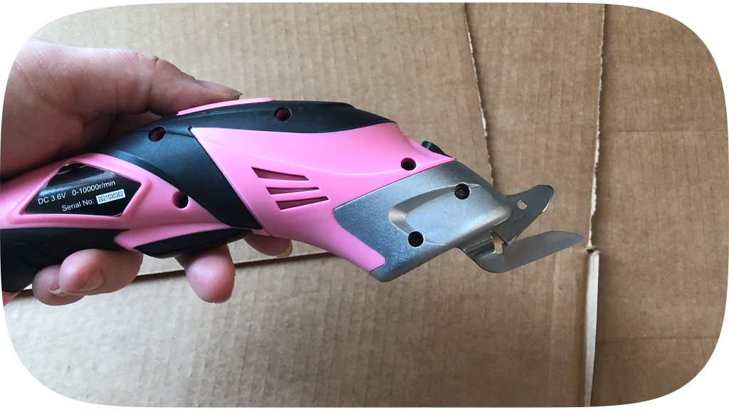 Hand holding a set of pink electric scissors.