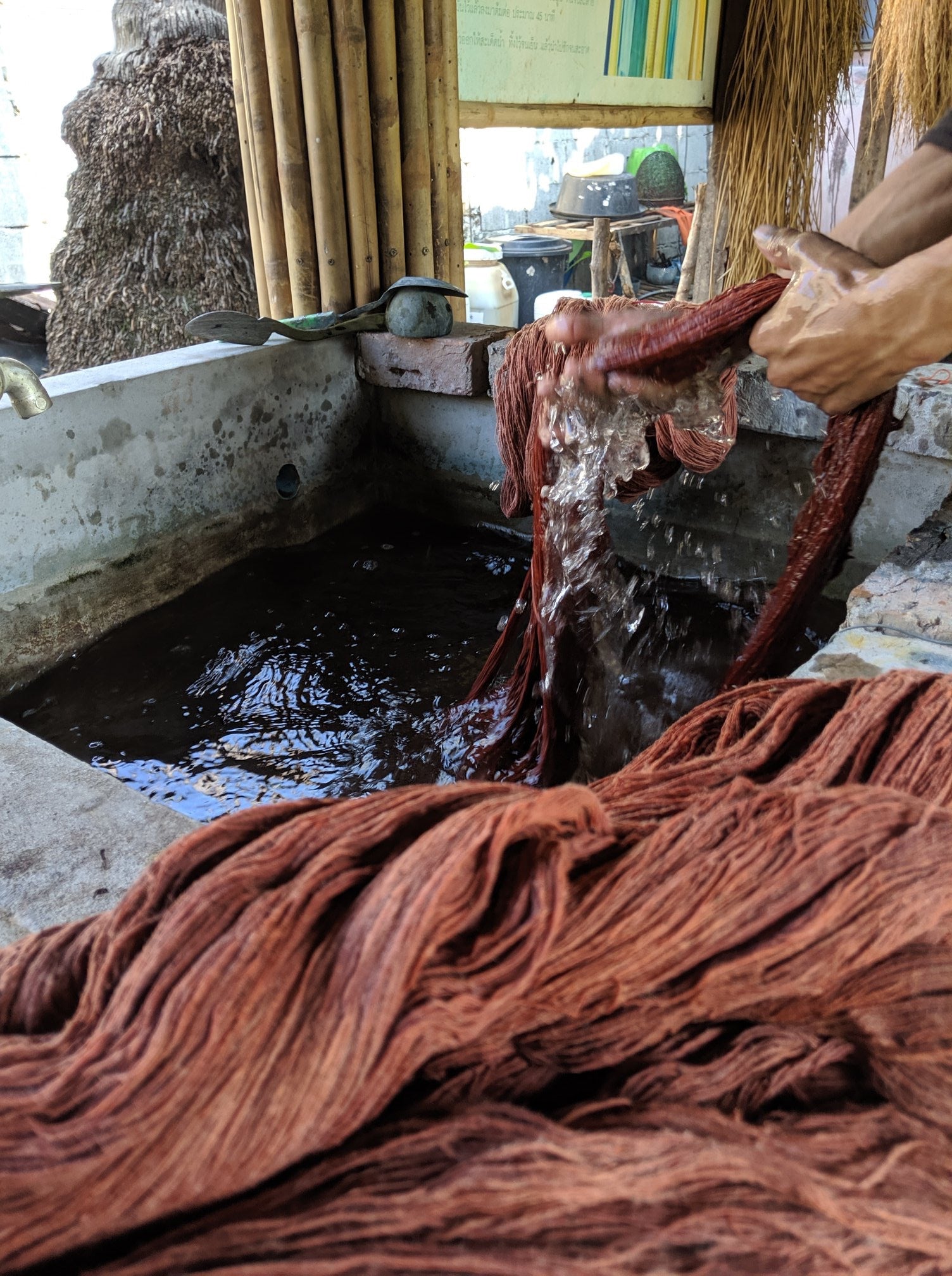 Close up of hands squeezing yarn through water as part of the natural dyeing process