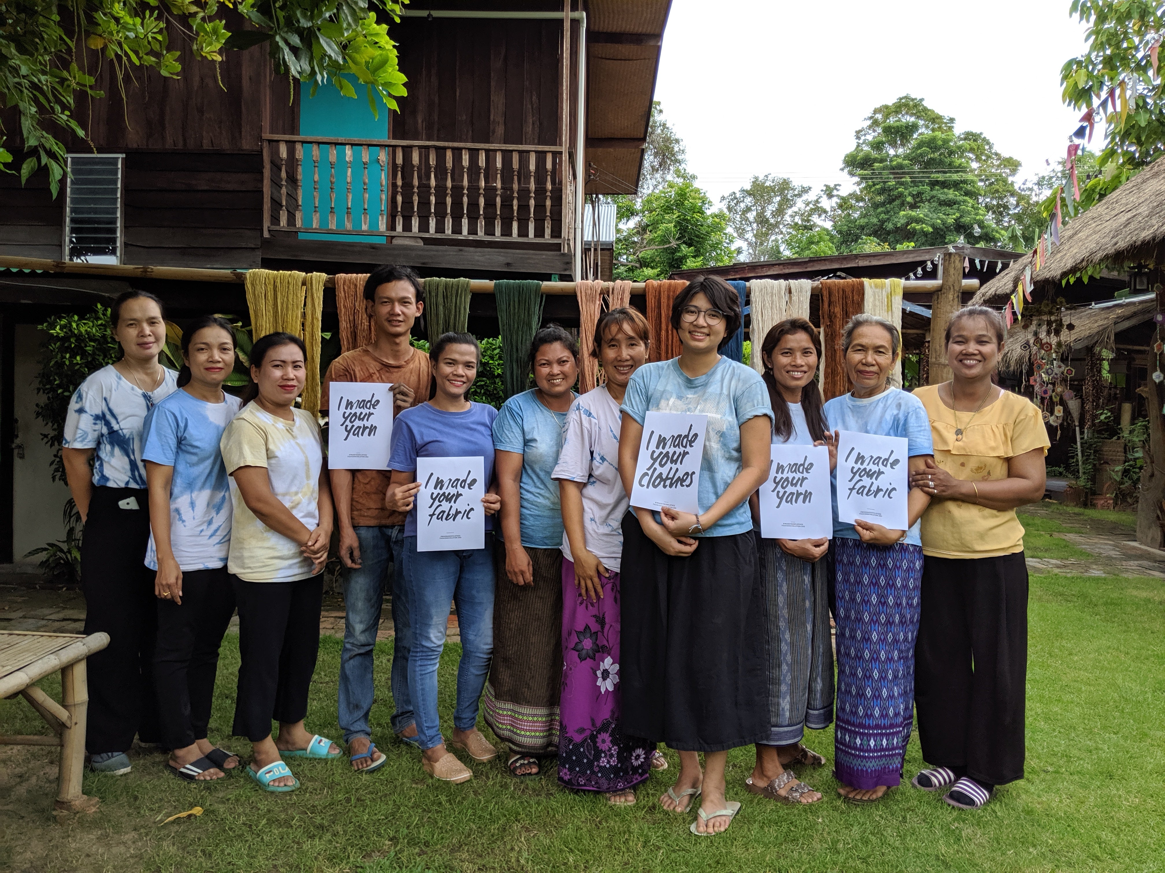 Tohsang Cotton Village workers standing with naturally dyed cotton and holding “Who Made My Clothes” posters