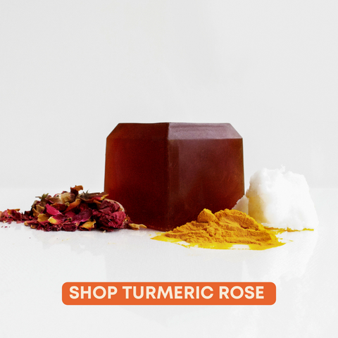 Orange face soap bar surrounded by ingredients like turmeric and rosebuds