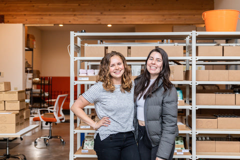 Photo of Genevieve and Marimar, co-owners of Eco Collective, standing and smiling the warehouse